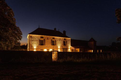 una casa vieja con luces encendidas por la noche en Clos des Dames de Lancharre - La Maison Des Vignes, en Chapaize