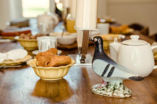 Una mesa con una figura de pájaro y un cuenco de pan. en Clos des Dames de Lancharre - La Maison Des Vignes, en Chapaize