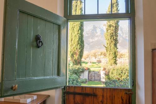 an open green door with a view of a garden at Huckleberry House - La Bruyere Farm in Tulbagh