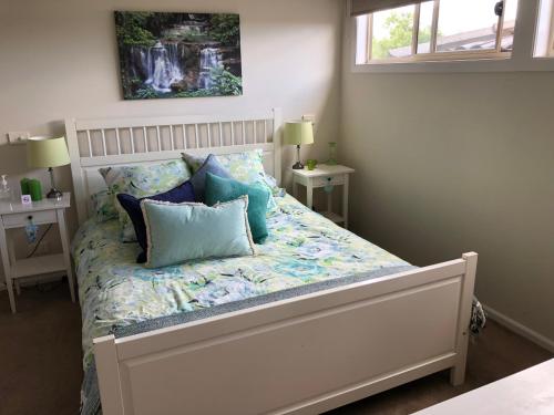 1 dormitorio con cama blanca y almohadas azules en 5 Star Room with own Bathroom - Singles, Couples, Families or Executives, en Glen Waverley