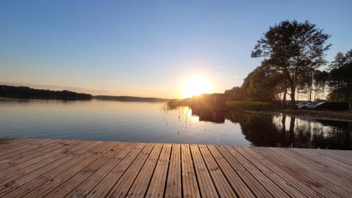 a sun setting over a lake with a wooden dock at "D" Domki na wodzie Barczewko 4 z 4 domków in Barczewko