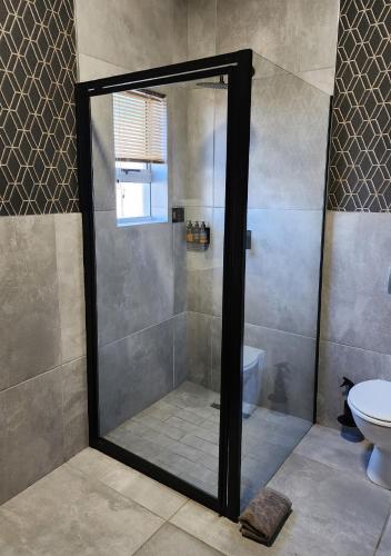 a shower with a glass door in a bathroom at Summer PALACE Guesthouse in Bloemfontein