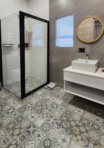 a bathroom with a shower and a sink and a mirror at Summer PALACE Guesthouse in Bloemfontein