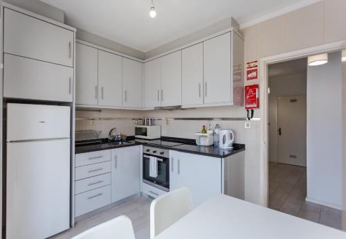 uma cozinha com armários brancos e electrodomésticos brancos em Wave Beach House em Vila do Conde