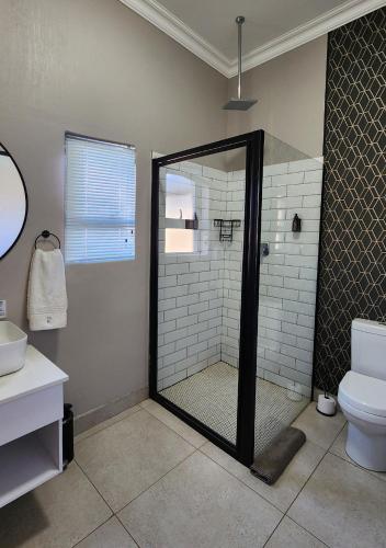 a bathroom with a glass shower with a toilet at Summer PALACE Guesthouse in Bloemfontein