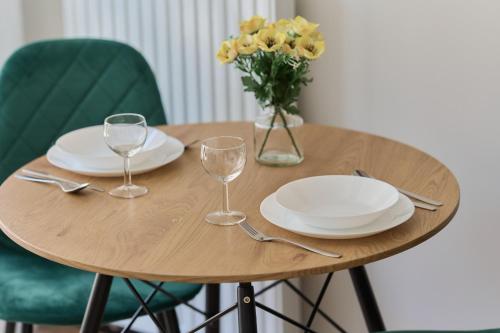 una mesa de madera con platos y vasos y un jarrón de flores en Cozy Studio Wroclaw Nadodrze for 3 Guests with Balcony by Renters, en Wroclaw