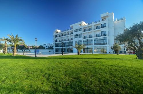 a white building with a park in front of it at Mc Palace Hotel Spa & Convention in Kyrenia