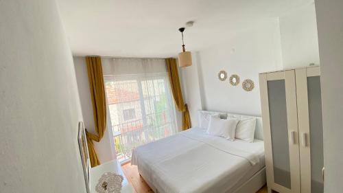 1 dormitorio con cama blanca y ventana en Pervin Hanım Konağı, en Alacati