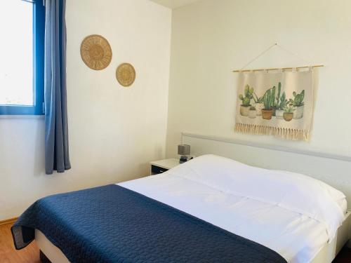 Un dormitorio con una cama con una manta azul y una ventana. en Karina Apartments, en Supetar