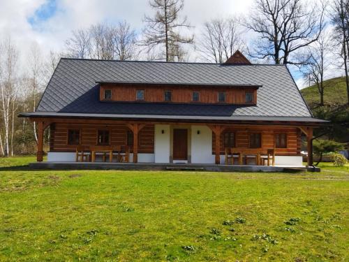 a large wooden cabin with a grass field in front of it at Nocuj in Teplice nad Metují