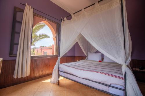 1 dormitorio con cama con dosel y ventana en RIAD LES DEUX MONDES, en Essaouira