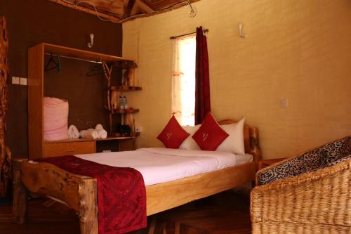 a bedroom with a bed and two chairs and a window at Brooks Lodge in Nakuru