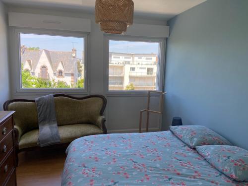 - une chambre avec un lit, une chaise et deux fenêtres dans l'établissement Appartement de ville et plage, à Concarneau