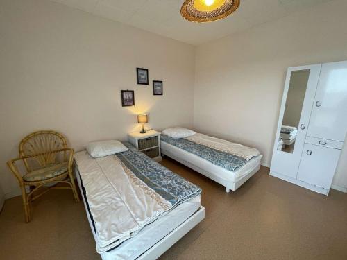 - 2 lits dans une chambre avec une chaise et un miroir dans l'établissement Appart. 2 pièces à 100m de la plage, 4 couchages, Parking, Lave-vaisselle, Animaux admis - FR-1-224C-133, à Saint-Jean-de-Monts