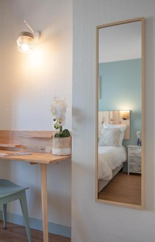 a bedroom with a mirror and a desk with a bed at Hôtel Le Rivage vue sur mer - Châtelaillon-plage in Châtelaillon-Plage