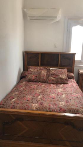 ein Bett mit einem Holzrahmen und einer Blumendecke in der Unterkunft قريه رمسيس الساحل الشمالي الكيلو ٤٥ in Dawwār Abū Maḩrūs