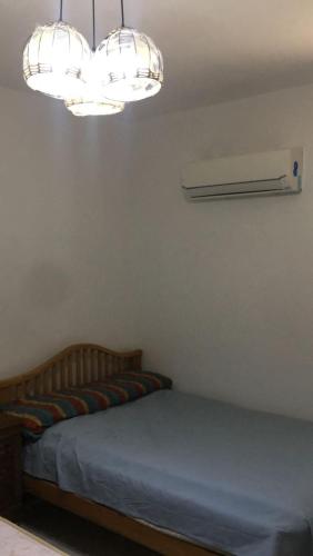 Bett in einem Zimmer mit 2 Kronleuchtern in der Unterkunft قريه رمسيس الساحل الشمالي الكيلو ٤٥ in Dawwār Abū Maḩrūs