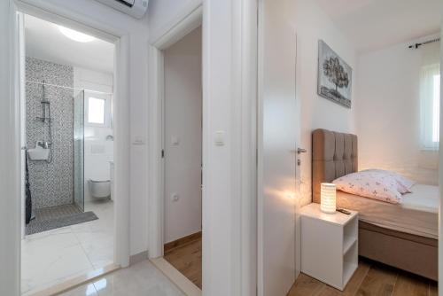 a white bathroom with a bed and a shower at Apartments Angelus in Trogir