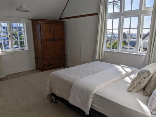 a bedroom with a bed and two windows at 1920s Classic Cozy 2-Bedroom Villa Apartment in Parnell in Auckland