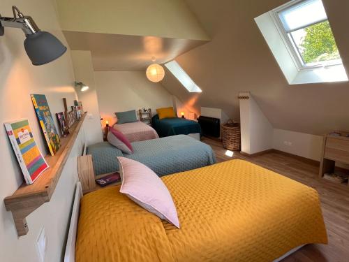 a attic bedroom with two beds and a window at Honfleur - grande maison familiale avec jardin in Honfleur