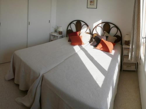 une chambre avec un grand lit avec des oreillers orange dans l'établissement Charmant appartement climatisé, parking, animaux admis - FR-1-100-221, à Cavalaire-sur-Mer