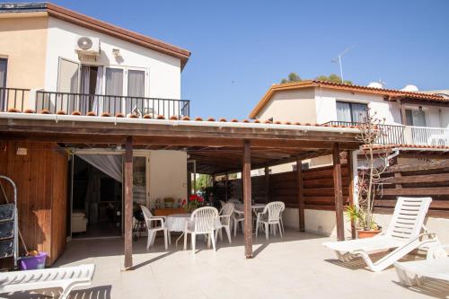 a patio with white chairs and tables and a building at Spyros No23 Charming Oceanview Maisonette in Meneou