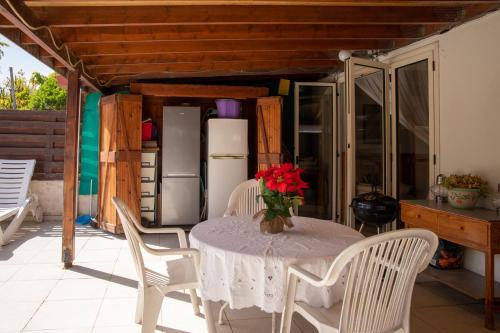 a table with a vase of red flowers on it at Spyros No23 Charming Oceanview Maisonette in Meneou