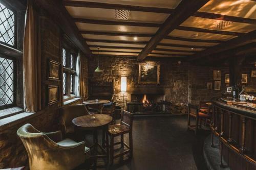 a living room with a fireplace and a table and chairs at The Peacock at Rowsley in Great Rowsley