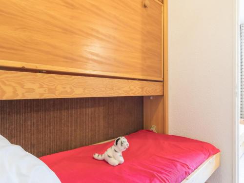 un petit chien blanc assis au-dessus d'un lit dans l'établissement Studio cosy 3 pers Montgenèvre, balcon sud, 20m² - FR-1-330D-117, à Montgenèvre