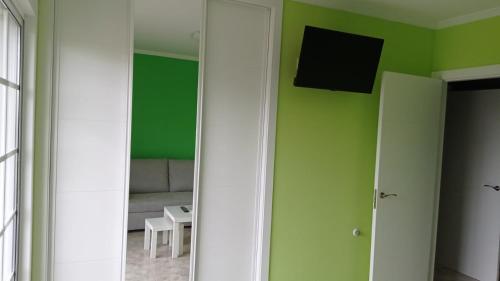 a living room with green walls and a television on the wall at Apartamentos M° Esther in A Lanzada