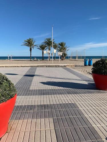 un paseo marítimo en una playa con palmeras y el océano en Apartamento Alicante San Juan playa 1ª línea, en Benimagrell