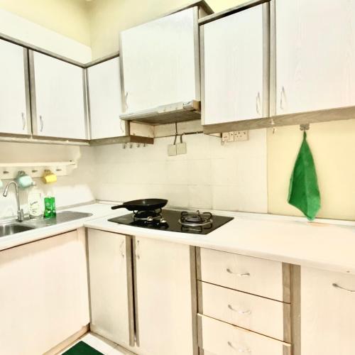 a kitchen with white cabinets and a stove top oven at NICE PLACE Selesa Hillhome Bukit Tinggi Bentong in Bentong