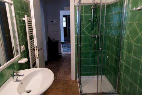 a green tiled bathroom with a sink and a shower at Villa Aurora by Mmega in Monte Rinaldo