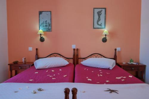 two beds in a bedroom with pink walls at Studios Zafiri in Naxos Chora