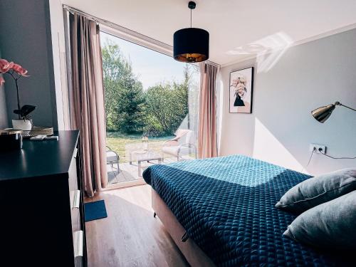 een slaapkamer met een bed en een groot raam bij Domek Golf i Jezioro in Tomaszkowo