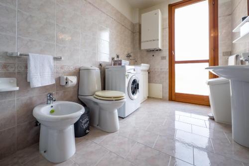 a bathroom with a toilet sink and a washing machine at Casa Vacanza Germano - Vivi un soggiorno da sogno - 160m2 di comfort e vista mare in Sicilia! in Pachino