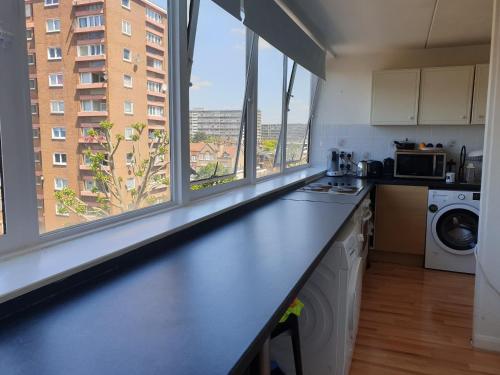 a kitchen with a counter top and large windows at Private ROOMS ONLY with SHARED bathroom near Elephant & Castle (zone 2) in London