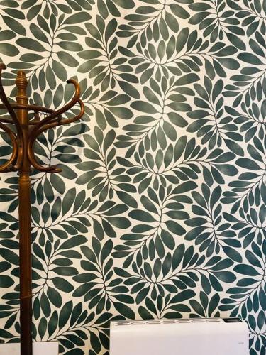 un mur avec un papier peint floral vert et blanc dans l'établissement Aux quatre Voûtes, à Saint-Marcel-dʼArdèche
