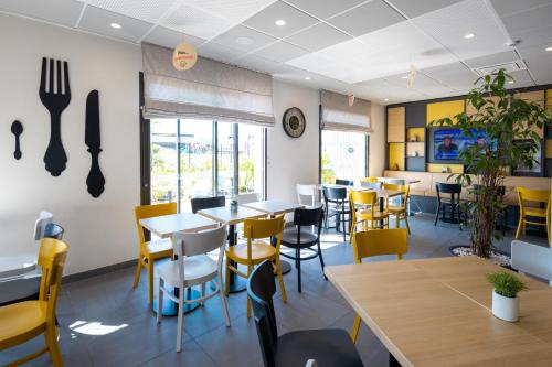 a dining room with tables and yellow chairs at B&B HOTEL Troyes Magasins d'usine in Troyes