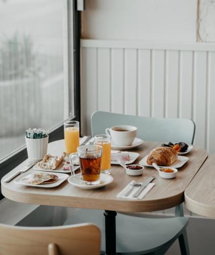 a wooden table with breakfast foods and drinks on it at Hôtel Le Rivage vue sur mer - Châtelaillon-plage in Châtelaillon-Plage