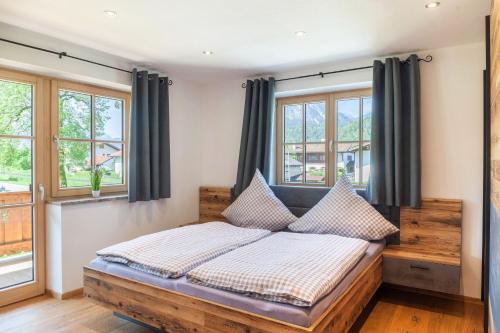 Schlafzimmer mit einem Holzbett und Fenstern in der Unterkunft Ferienwohnung Johanni in Farchant