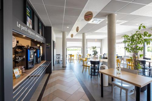 a restaurant with tables and chairs in a cafeteria at B&B HOTEL Troyes Magasins d'usine in Troyes