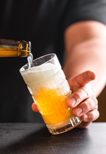a person is holding a glass of beer at Hôtel Le Rivage vue sur mer - Châtelaillon-plage in Châtelaillon-Plage