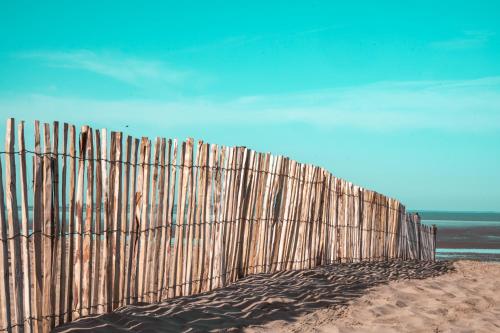 a wooden fence on the beach near the ocean at Hôtel Le Rivage vue sur mer - Châtelaillon-plage in Châtelaillon-Plage