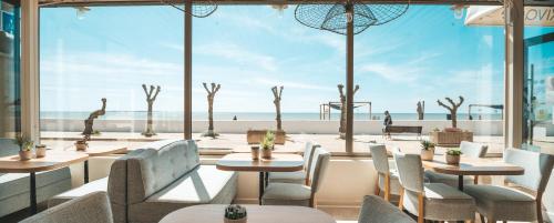 a restaurant with tables and chairs and a view of the beach at Hôtel Le Rivage vue sur mer - Châtelaillon-plage in Châtelaillon-Plage