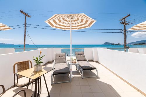 patio z krzesłami, stołami i parasolem w obiekcie Mouria Studios & Apartments w Laganas