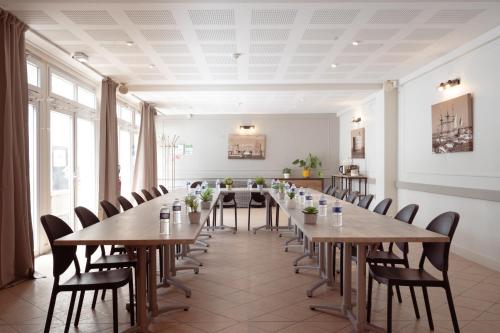 Habitación grande con mesas y sillas de madera. en Hôtel Le Rivage vue sur mer - Châtelaillon-plage, en Châtelaillon-Plage