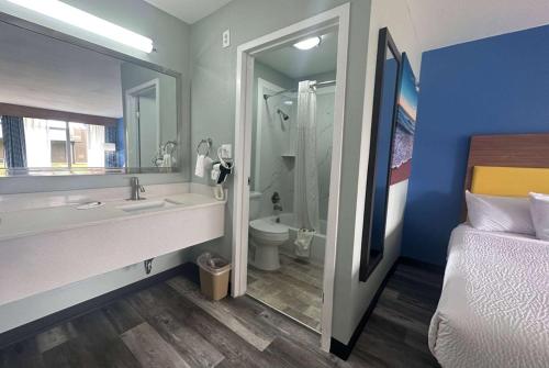 a bathroom with a sink and a toilet and a bed at Days Inn & Suites by Wyndham Jennings in Jennings
