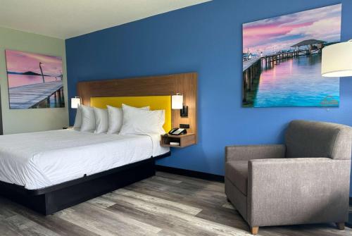a hotel room with a bed and a chair at Days Inn & Suites by Wyndham Jennings in Jennings