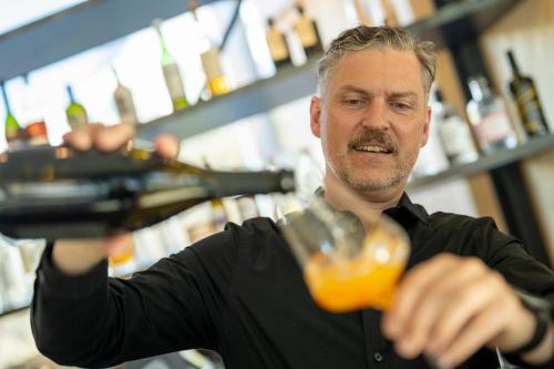 a man pouring a drink in a bar at Hotel Arnica Scuol - Adults Only in Scuol